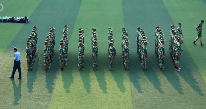 Fotografia em cores de soldados em formação em campo gramado.